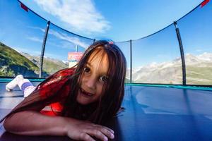 Kleines Mädchen spielt auf dem Spielplatz auf dem wunderschönen Landschaftshintergrund in den Bergen foto