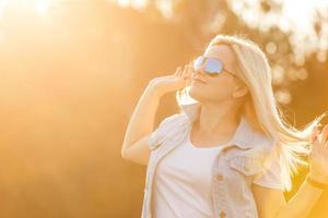 attraktive junge Frau, die ihre Zeit draußen im Park mit Sonnenuntergang im Hintergrund genießt. foto