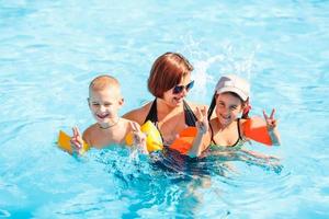 schöne junge mutter mit kleinem sohn und tochter im pool. foto