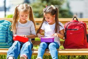 Grundschulkinder sitzen mit Lunchpaketen foto