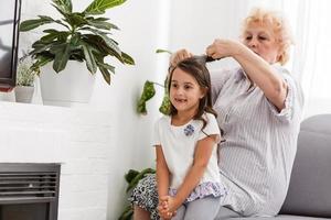 Großmutter macht Hairslyle zu ihrer Enkelin. familiärer Inhalt foto