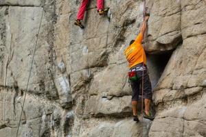 mann mit einem seil, das sich mit dem klettersport auf dem felsen beschäftigt. foto