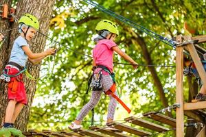 Abenteuer Klettern Hochseilpark - Kinder im Seilpark im Berg Helm und Sicherheitsausrüstung foto