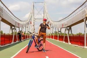 junger hübscher athletischer mann, der mit fahrrad im bunten herbstpark steht. Hintergrund der Herbstsaison. männlicher radfahrer auf der straße mit abgefallenen blättern foto