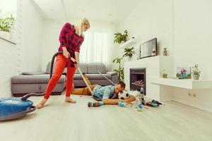 Frau reinigt die Wohnung, während der Mann ruht foto