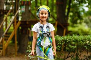 glückliches Schulmädchen, das Aktivität in einem Kletterabenteuerpark an einem Sommertag genießt foto