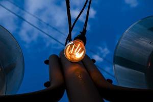 Nahaufnahme eines Glühfadens im Edison-Stil auf einer Glühbirne vor einem bewölkten Himmel. Energiekrise. foto