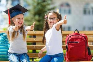 erfolgreiches weibliches karrierekonzept. Fröhlicher Mathematikstudent des kleinen Mädchens im Abschlusshut auf Schulhintergrund foto