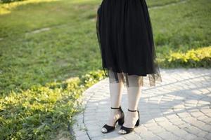 schwarzes Kleid und schwarze Schuhe für Mädchen. schwarze Kleidung im Sommer. Details der Zeremonie. foto