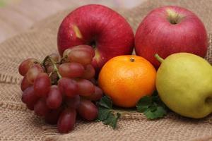 Früchte mit Vitamin C, die für den Körper von Vorteil sind. auf Sackleinen legen - Orange, Traube, Apfel, Guave