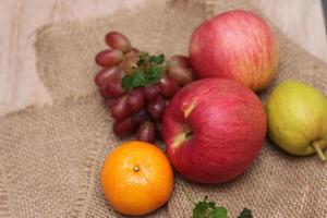 Früchte mit Vitamin C, die für den Körper von Vorteil sind. auf Sackleinen legen - Orange, Traube, Apfel, Guave foto