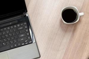 Laptop mit schwarzer Kaffeetasse auf dem Tisch foto
