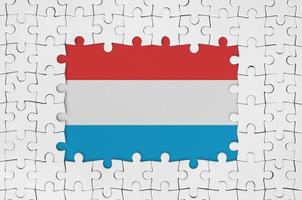 Luxemburg-Flagge im Rahmen aus weißen Puzzleteilen mit fehlendem Mittelteil foto