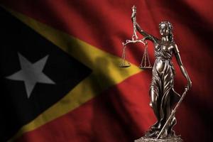 Timor-Leste-Flagge mit Statue der Justitia und Gerichtswaage im dunklen Raum. Konzept von Urteil und Bestrafung foto