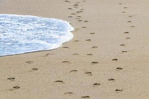 fußabdruck fußspuren auf dem strandsand am wasser mexiko. foto