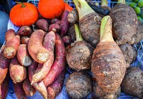Haufen süßer Yamswurzeln, lila und Taro-Wurzelkartoffeln und Kürbishintergrund foto