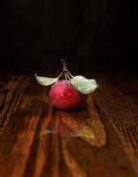 roter reifer Apfel mit Blättern auf einem Holztisch. foto