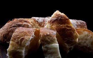 in Scheiben geschnittenes frisches Baguette mit Kräutern und Gewürzen auf einem Holztisch. Kunstbrot. foto