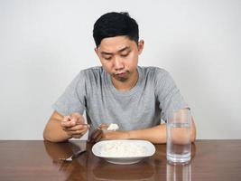 junger mann fühlt sich gelangweilt essen will nicht reis auf dem tisch essen foto