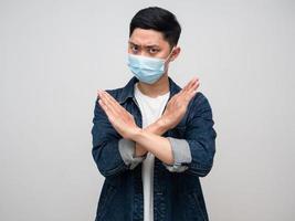 asiatischer mann jeanshemd tragen medizinische maske zeigen kreuzarm verweigern zeichen, mann hand abgelehnt foto