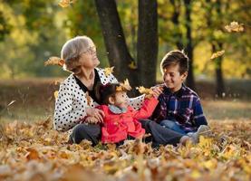 glückliche großmutter, enkelin und enkel, die im park spielen foto