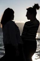 Silhouetten von Freundinnen bei Sonnenuntergang, die sich umarmen. foto