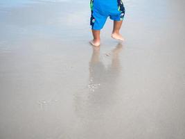 Kind, das am Sandstrand spazieren geht, Fußabdruck von Sandkindern foto