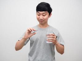 asiatischer mann, der in der hand medizin mit glaswasser sucht, guter gesunder mann foto