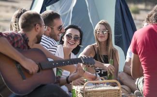 sommer, ferien, urlaub, musik, fröhliches menschenkonzept - gruppe von freunden mit gitarre, die spaß am strand haben foto