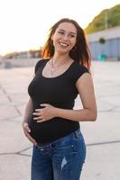 Porträt einer hispanischen schwangeren Frau, die bei Sonnenuntergang auf dem Damm spazieren geht. schwangerschafts- und mutterschaftskonzept. foto