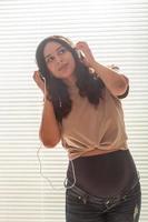 schwangere frau hört zu hause musik über kopfhörer und tanzt foto