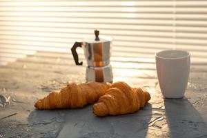 Frühstück mit Croissant und Mokkakanne. Morgenmahlzeit und Frühstückskonzept. foto