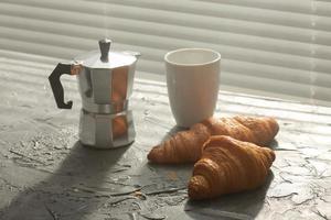 Frühstück mit Croissant und Kaffee- und Mokkakanne. Morgenmahlzeit und Frühstückskonzept. foto