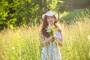 Frau, die an einem sonnigen Sommertag auf einem Feld spazieren geht. foto