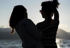 Silhouetten von Freundinnen bei Sonnenuntergang, die sich umarmen. foto