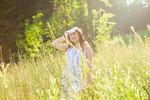 Frau, die an einem sonnigen Sommertag auf einem Feld spazieren geht. foto