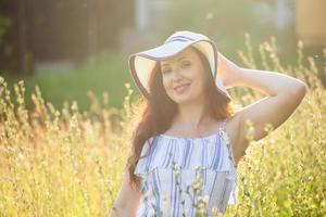 Frau, die an einem sonnigen Sommertag auf einem Feld spazieren geht. foto