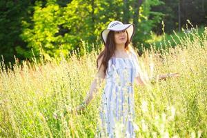 Frau, die an einem sonnigen Sommertag auf einem Feld spazieren geht. foto