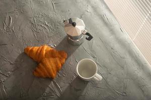 frühstück mit croissant und tasse und moka-kanne. Morgenmahlzeit und Frühstückskonzept. foto