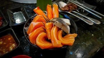Nahaufnahme von frisch geschnittenem Lachs und Thunfisch in schwarzer Schüssel mit Sojasauce auf schwarzem Tisch im japanischen Restaurant. japanisches essen und frisches fischmehl foto