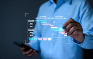 Projektmanager, der am Tablet arbeitet und die Fortschrittsplanung von Aufgaben und Meilensteinen mit der Gantt-Diagramm-Planungsschnittstelle für das Unternehmen auf dem virtuellen Bildschirm aktualisiert. Projektmanagementsystem für Unternehmen. foto