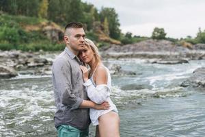 glückliches junges Paar verliebte Reisende, die sich im Gebirgsfluss küssen foto