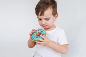 lustiger süßer Kleinkindjunge mit Donut auf dem weißen Hintergrund foto