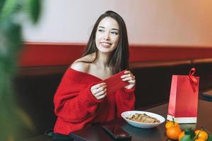 schöne junge asiatische frau in roter kleidung, die asiatisches essen mit rotem umschlag im restaurant isst und das chinesische neujahr feiert foto