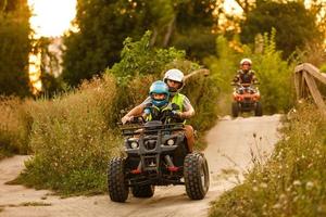 kleiner Junge mit Ausbilder auf einem Quad foto