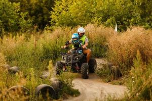 kleiner Junge mit Ausbilder auf einem Quad foto