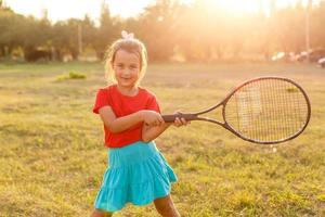 sportliches kleines Mädchen, das sich darauf vorbereitet, Tennisball zu dienen. Nahaufnahme eines schönen Yong-Mädchens, das Tennisball und Schläger hält. Kindertennisspieler foto
