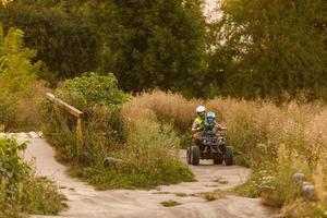 kleiner Junge mit Ausbilder auf einem Quad foto