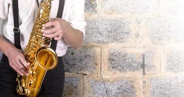 junger Mann in einem weißen Hemd mit Saxophon foto