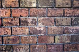 Rote Backsteinmauer mit zerkratzten Inschriften auf Zemun foto